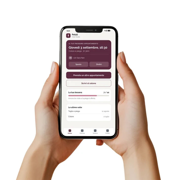Un telefono tenuto in mano, con aperta l’app di un salone: il prossimo appuntamento e la tessera a punti